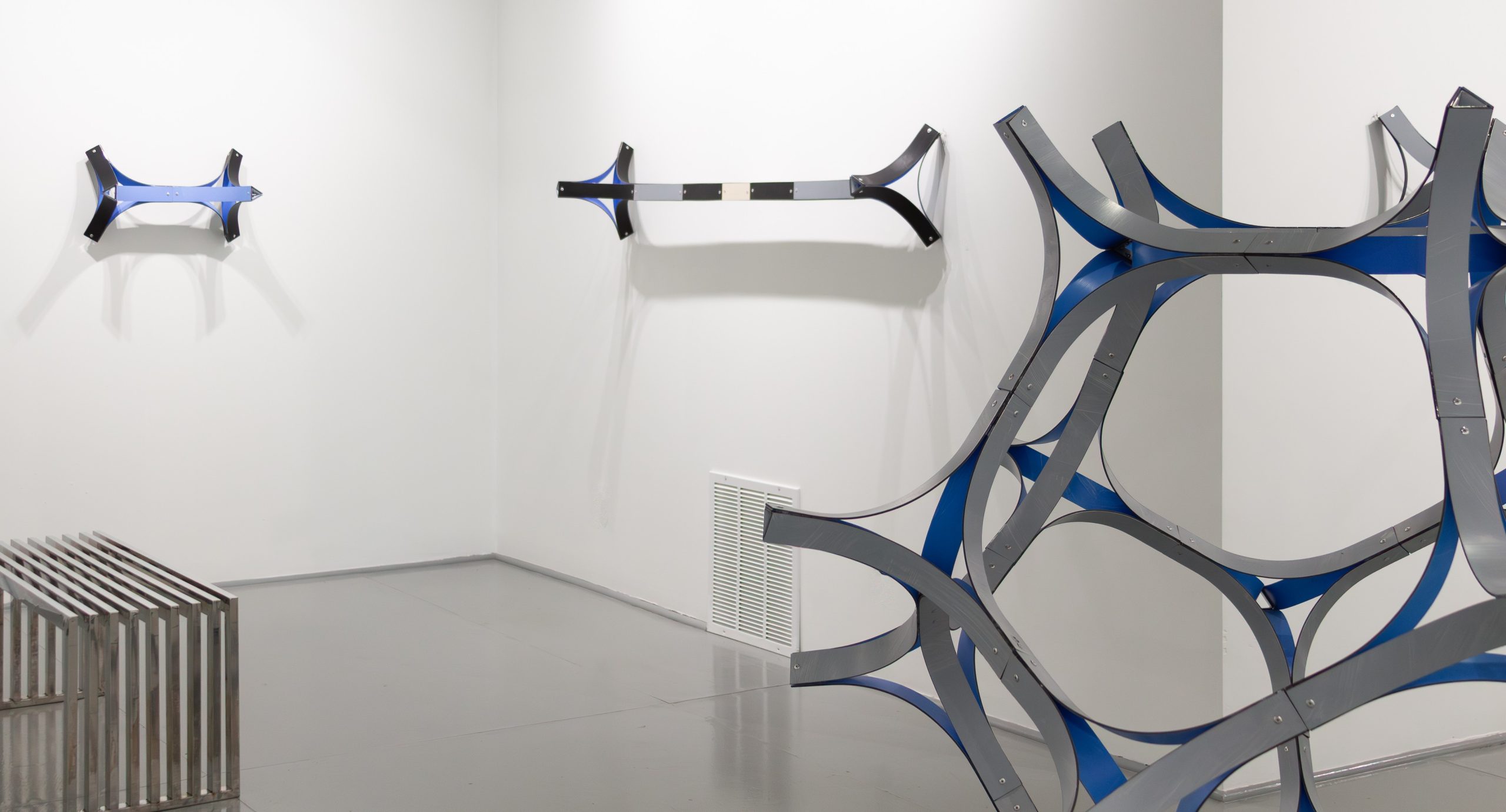 Installation view of Equidistant solo exhibition by Cesar Lopez at Gallery Bogart Kansas City, featuring large-scale geometric sculptures and wall-mounted works exploring themes of migration and identity.